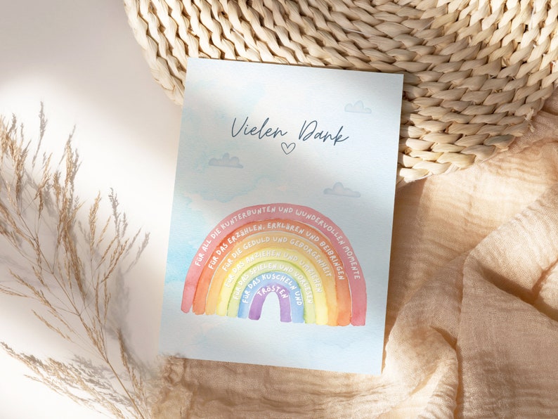Op de afbeelding: Een kaart met een regenboogontwerp en de tekst "Vielen Dank" (Duits voor "Bedankt") met een hartje. De regenboog heeft tekst eromheen die zegt "Voor al die kleurrijke en prachtige momenten", "Voor het vertellen, uitleggen en leren", "Voor het geduld en begrip", "Voor het knuffelen en kroelen", "Voor het lachen en de tranen".