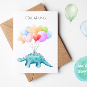 May include: A white card with the word "Einladung" printed in black. A green dinosaur with a purple spine is holding up a bunch of colorful balloons. The balloons are pink, red, orange, yellow, green, and blue. The card is sitting on a brown envelope. A green watercolor circle with the text "Made in Germany" is in the lower right corner.