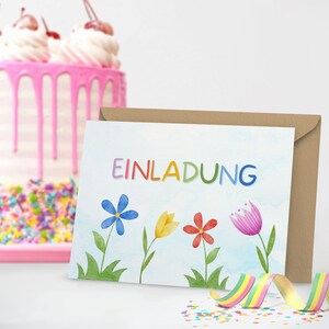 May include: A colorful invitation card with the word "EINLADUNG" in rainbow letters and a watercolor illustration of flowers. The card is on a brown envelope.