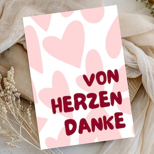 May include: A rectangular greeting card featuring a white background with a repeating pattern of light pink hearts. The text VON HERZEN DANKE is printed in the center in a bold, dark red, rounded sans-serif font.