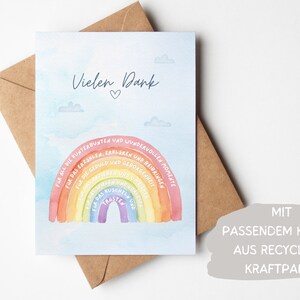Op de afbeelding: Een lichtblauwe kaart met een regenboogontwerp en de tekst "Vielen Dank" (Duits voor "Bedankt") en een hartje. De regenboog heeft Duitse woorden die verschillende soorten ondersteuning beschrijven. De kaart ligt op een bruine envelop met de tekst "MIT PASSENDEM KUVERT AUS RECYCLETEM KRAFTPAPIER" (Duits voor "Met bijpassende envelop van gerecycled kraftpapier").