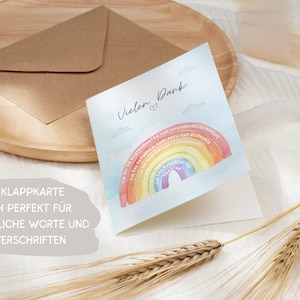 Op de afbeelding: Een gevouwen kaart met een aquarel regenboogontwerp en de tekst "Vielen Dank" (Duits voor "Bedankt"). De regenboog heeft Duitse woorden erop geschreven. De kaart ligt op een houten oppervlak met een bruine envelop en tarwehalmen.