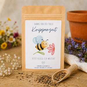 Könnte beinhalten: Ein brauner Papierbeutel mit Blumensamen und einem Etikett, das eine Comic-Biene, eine rosa Blume und den Text zeigt: DANKE FÜR DIE TOLLE Krippenzeit JETZT FLIEGE ICH WEITER! SAMENMIX BIENENWIESE AUSSAAT VON MÄRZ BIS OKTOBER.