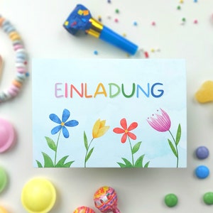 May include: A blue and white card with the word "EINLADUNG" in rainbow letters. The card has a watercolor background with three flowers: a blue flower, a yellow flower, and a red flower.