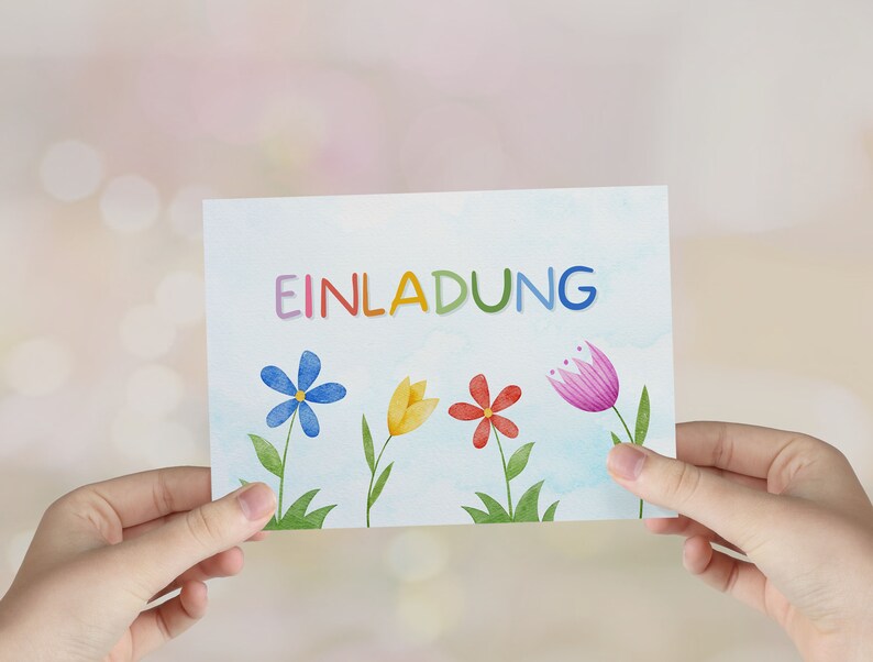 May include: A white card with the word "EINLADUNG" written in rainbow colors. The card is decorated with colorful flowers and has a watercolor background.