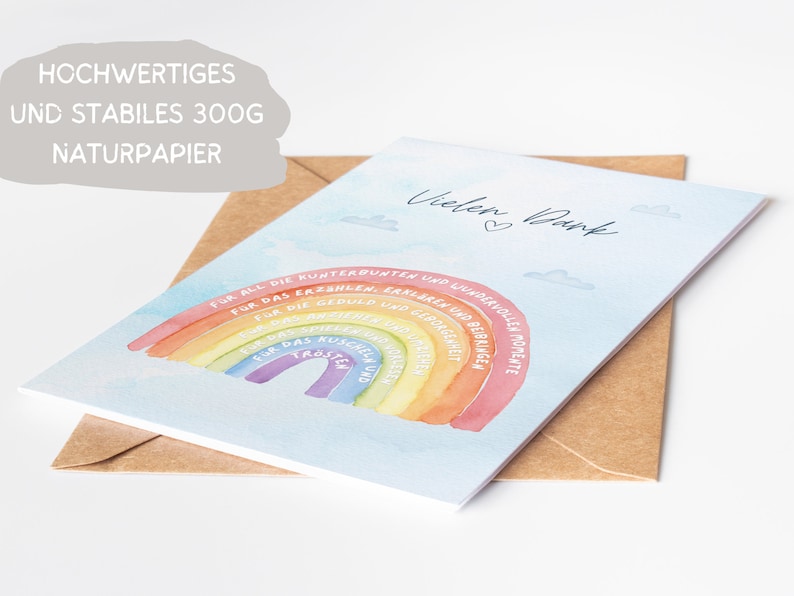 Op de afbeelding: Een lichtblauwe kaart met een regenboog en de tekst "Vielen Dank" in wit. De regenboog heeft tekst op elke streep, waaronder "Voor alle kleurrijke en prachtige momenten", "Voor het geduld en begrip", "Voor de knuffels en knuffels", "Voor het lachen en de vreugde", "Voor het vertrouwen en de troost", "Voor de kussen en de liefde", "Voor de verhalen en liedjes".