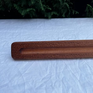 May include: A close-up of a wooden tray with a textured surface and a groove running along the length of the tray.