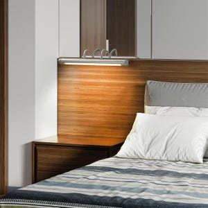 May include: A modern bedroom scene featuring a wooden headboard with a built-in light fixture. The bed has white pillows and a striped comforter. A dark wood nightstand is visible on the left.
