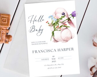 May include: A baby shower invitation with a watercolor illustration of a white bunny holding a bouquet of flowers. The text reads "Hello Baby" and includes the name "Francisca Harper", the date "May 10, 2023", and the time "3 PM".