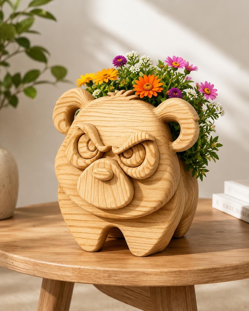 K&ouml;nnte beinhalten: Ein Holzblumentopf in Form eines w&uuml;tenden B&auml;rengesichts, gef&uuml;llt mit bunten Blumen. Der Pflanztopf ist aus hellem Holz gefertigt und steht auf einem runden Holztisch. Die Blumen umfassen orange, gelbe, lila und wei&szlig;e Bl&uuml;ten.