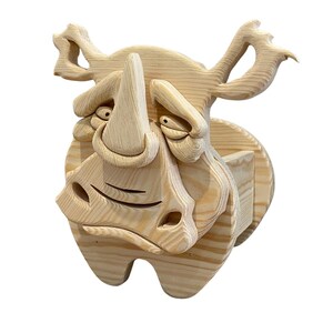 May include: A whimsical wooden rhino sculpture with a cartoonish design. The rhino is carved from light-colored wood, featuring exaggerated facial features, including a large horn, expressive eyes, and a wide, smiling mouth. The sculpture is mounted on a circular wooden base.