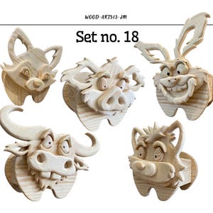 Pode incluir: Conjunto de cinco esculturas de cabeças de animais em madeira, incluindo uma raposa, um javali, um coelho, um touro e uma criatura com cabelo pontudo. Cada peça é esculpida em madeira clara e apresenta expressões faciais exageradas. O texto "Set no. 18" é visível.