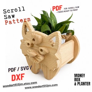 May include: A wooden scroll saw pattern for a cat-shaped planter or money box. The planter is made of light-colored wood and features a cat face design. The image includes the text "Scroll Saw Pattern", "PDF", "PDF / SVG / DXF", and website addresses.