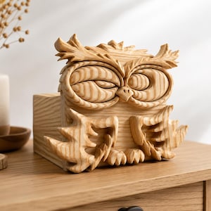 May include: A detailed wooden owl sculpture. The owl features carved feather and eye details, crafted from light-coloured wood. The sculpture is displayed on a wooden surface, showcasing the craftsmanship.