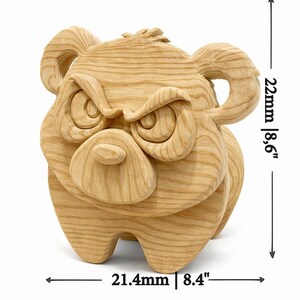K&ouml;nnte beinhalten: Holzskulptur eines w&uuml;tenden B&auml;ren mit gerunzelten Augenbrauen und einem m&uuml;rrischen Gesichtsausdruck. Der B&auml;r ist aus hellfarbenem Holz geschnitzt und ist 21,4 cm breit und 22 cm hoch.