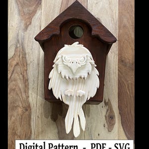 Puede incluir: Una casita de pájaros de madera con un diseño de búho tallado. El búho está pintado en un color madera natural y tiene una cara detallada con ojos grandes. La casita de pájaros está pintada en un color marrón oscuro y tiene una pequeña abertura para que los pájaros puedan entrar.