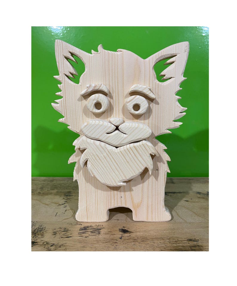 May include: A wooden cat-shaped box with a surprised expression. The box is made of light-colored wood and features cut-out ears, eyes, and a beard. The cat is standing upright, and the box appears to be a decorative item or storage container.