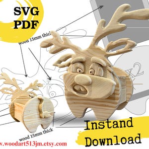 May include: A light-colored wooden reindeer figurine with large antlers and a cartoonish expression, shown alongside technical line drawings and text labels indicating wood 15mm thick and wood 10mm thick, with SVG PDF and Instand Download text.