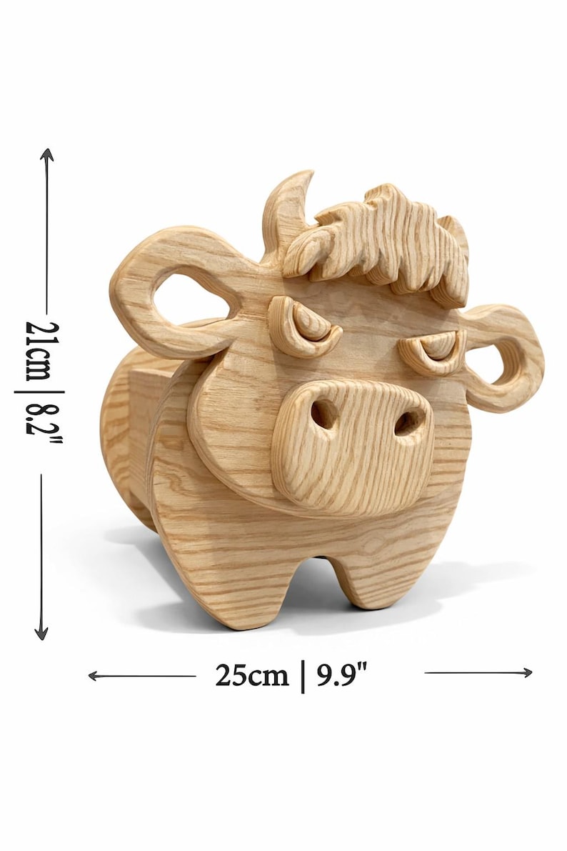 K&ouml;nnte beinhalten: Dekorative Kuh aus Holz. Die Kuh ist aus hellem Holz gefertigt und misst 21 cm in der H&ouml;he und 25 cm in der Breite. Sie weist geschnitzte Details wie H&ouml;rner, Ohren und ein stilisiertes Gesicht auf. Der Artikel ist zum Aufstellen konzipiert.