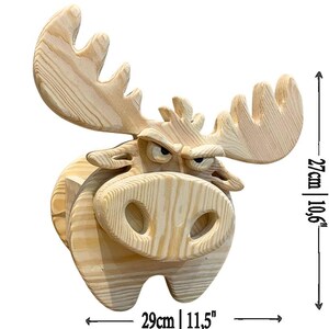 K&ouml;nnte beinhalten: Holzskulptur eines Elchs mit w&uuml;tendem Gesichtsausdruck. Die Skulptur ist aus hellem Holz gefertigt und hat ein gro&szlig;es Geweih. Sie ist 29 cm breit und 27 cm hoch.