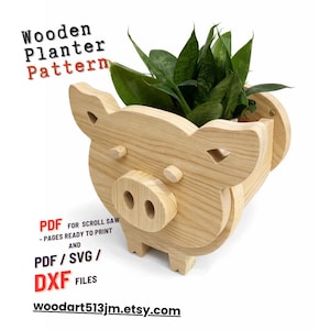 Op de afbeelding: Een houten plantenbak in de vorm van een varken, met een groene plant erin. De plantenbak is gemaakt van lichtgekleurd hout en heeft een gedetailleerd ontwerp. Tekst op de afbeelding luidt "Wooden Planter Pattern" en "woodart513jm.etsy.com".