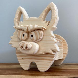 May include: A wooden wolf sculpture with a cartoonish design. The wolf has detailed eyes, a prominent nose, and pointed ears. The sculpture is made from light-coloured wood. The design is whimsical and would suit a child's room or a quirky home.
