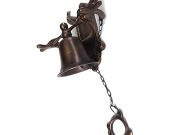 May include: A brass bell with a decorative ornate design, hanging from a chain with a pull ring. The bell is mounted on a wall bracket.