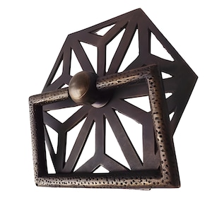 May include: A geometric brass cabinet pull with a textured finish. The pull has a square shape with a circular knob in the center.