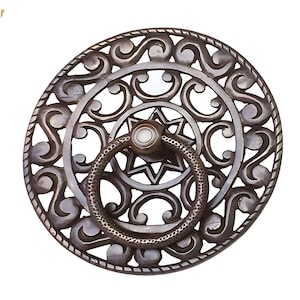 May include: A circular, ornate, metal door knocker with a star-shaped design and a ring handle. The knocker is made of a dark, aged metal and has a detailed, intricate pattern.