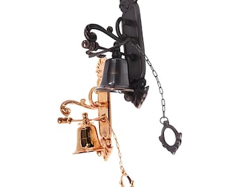 May include: Ornate wall-mounted bell with a dark bronze finish, featuring a decorative backplate and a pull chain. A smaller, gold-toned bell is mounted below. The design includes scrolling details and a classic aesthetic.