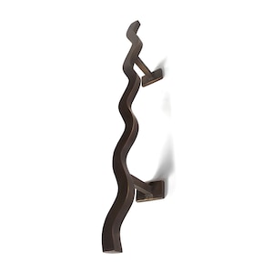 Pode incluir: Um toalheiro de metal marrom escuro ondulado com dois suportes quadrados. O toalheiro est&aacute; montado verticalmente em um fundo branco.