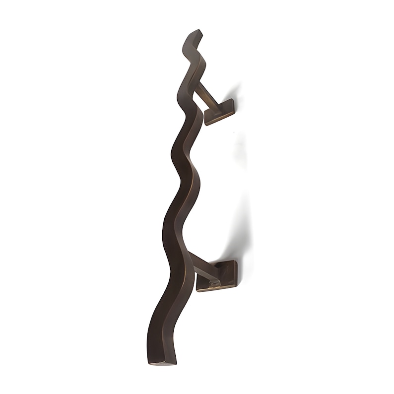 Pode incluir: Um toalheiro de metal marrom escuro ondulado com dois suportes quadrados. O toalheiro est&aacute; montado verticalmente em um fundo branco.