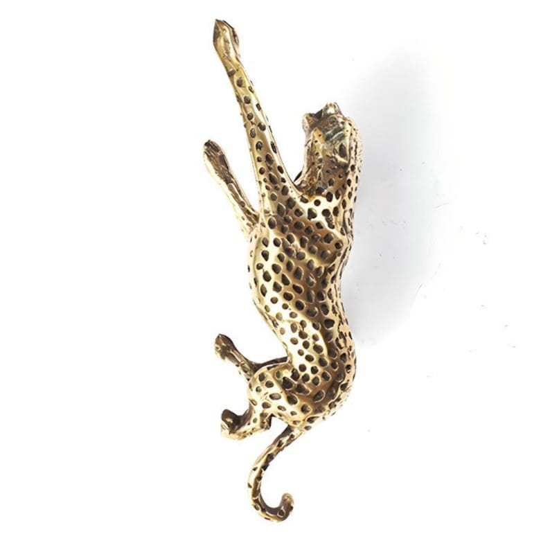 May include: A gold-colored metal sculpture of a cheetah leaping upwards. The cheetah is detailed with a spotted pattern.