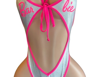 May include: Silver swimsuit with pink trim and the word "Barbie" in pink script. The swimsuit has a keyhole cutout and a pink bow. A pink Barbie silhouette is on the front.