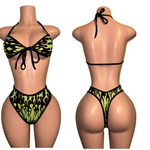 May include: Black and green bikini with a flame pattern. The top is a halter style with a tie in the front. The bottom is a high-waisted style with a cheeky cut.