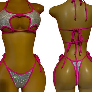 May include: A two-piece swimsuit with a pink and silver design. The top has a halter style with a heart-shaped cutout in the front. The bottom is a cheeky style with a low rise and ties on the sides.