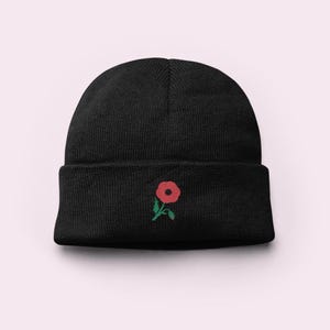 May include: Black beanie with a red poppy embroidered on the front.