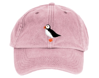 May include: A pink denim baseball cap with an embroidered image of a puffin.