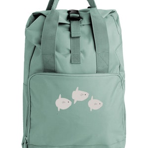 Puede incluir: Una mochila verde claro con una hebilla negra y tres ilustraciones de peces blancos en la parte delantera.