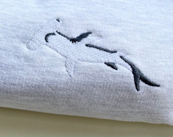 May include: A gray sweatshirt with a white embroidered hammerhead shark design.