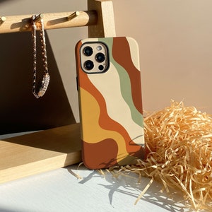 Op de afbeelding: Een telefoonhoesje met een kleurrijk abstract ontwerp met golvende lijnen in tinten bruin, geel, groen en crème. Het hoesje is ontworpen voor een telefoon met een drievoudige lenscamera.