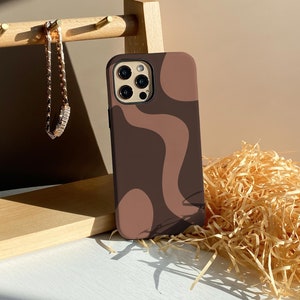 Può includere: Una custodia per telefono astratta marrone e rosa con un design geometrico. La custodia è realizzata in silicone e ha una finitura opaca.