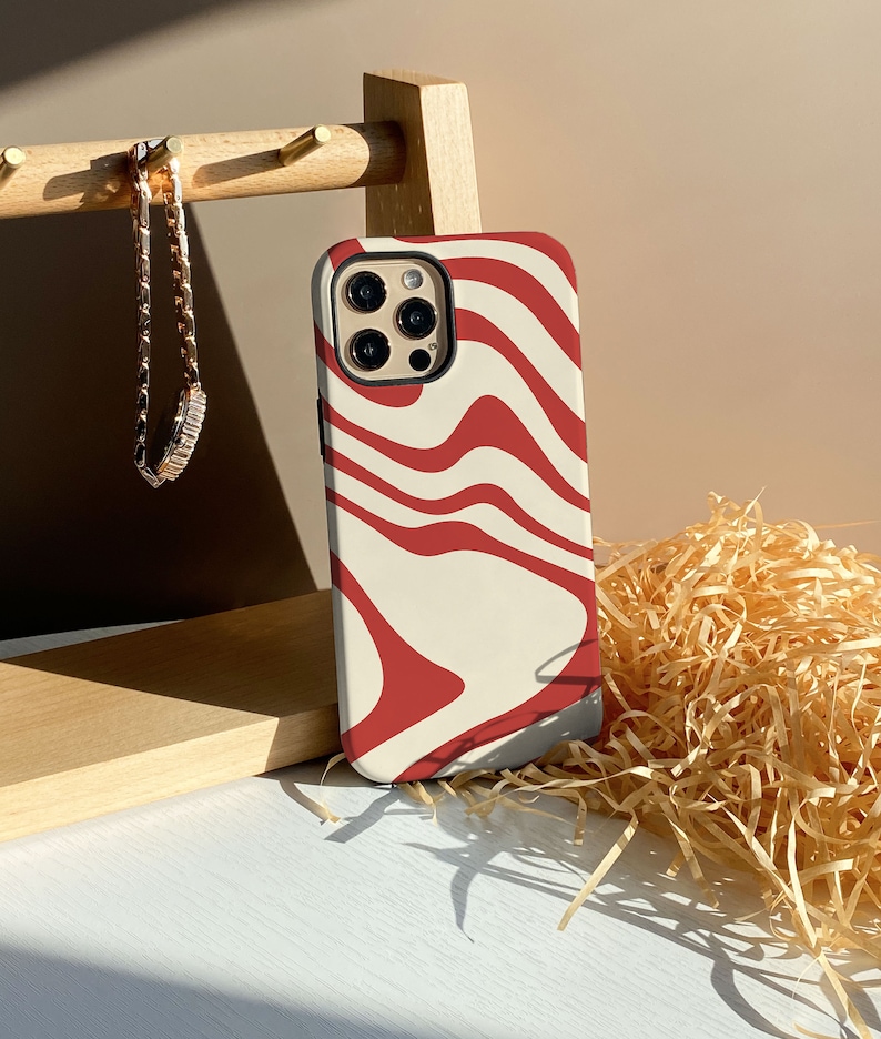 May include: A white and red swirl patterned phone case for an iPhone.