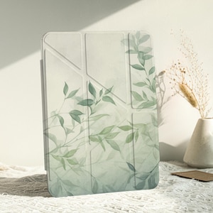 Könnte beinhalten: Eine weiße Tablethülle mit einem Aquarelldesign aus grünen Blättern. Die Hülle hat ein geometrisches Muster und einen dezenten grünen Hintergrund.