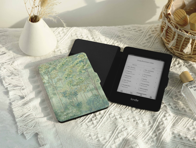 May include: A black Kindle e-reader with a forest scene cover. The e-reader is open to a page with a list of books. The cover is a green and white pattern of trees.