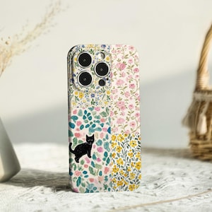 Può includere: Custodia per telefono con motivo floreale patchwork e illustrazione di un gatto nero. La custodia presenta fiori e foglie rosa, gialli e blu. La custodia del telefono ha un ritaglio per la fotocamera.