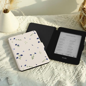May include: A black Kindle e-reader with a floral patterned case. The e-reader screen displays a list of books and the word "Kindle".
