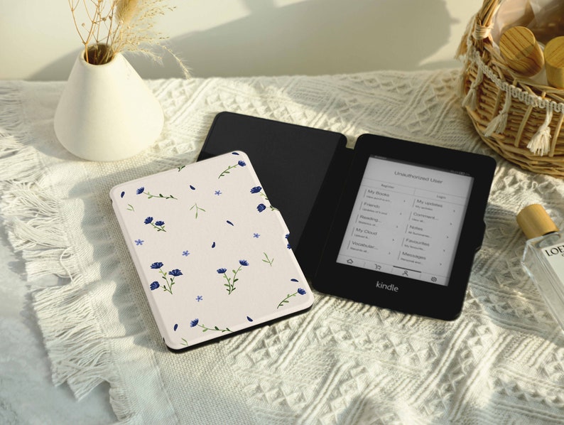 May include: A black Kindle e-reader with a floral patterned case. The e-reader screen displays a list of books and the word "Kindle".