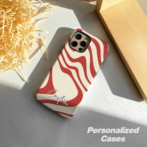 May include: A white and red phone case with a wavy pattern and the word "Custom" written in black. The case is designed for a phone with a camera bump.