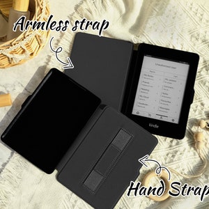 May include: Black Kindle e-reader with a black case. The case has a strap on the back for holding the e-reader and a strap on the side for holding the e-reader in your hand.